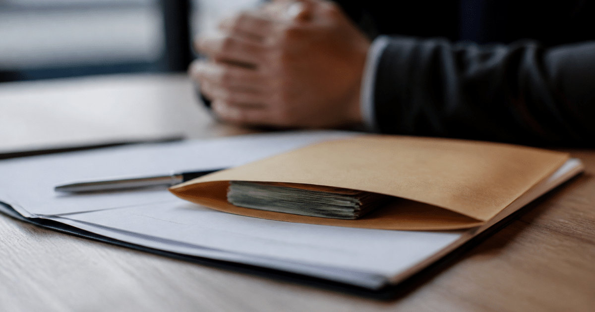 Enveloppe contenant billets argent posée sur contrat immobilier signé