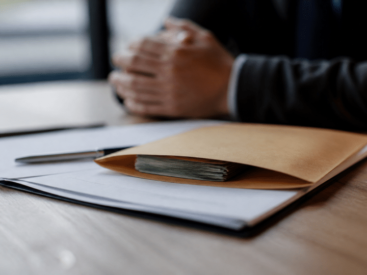Enveloppe contenant billets argent posée sur contrat immobilier signé