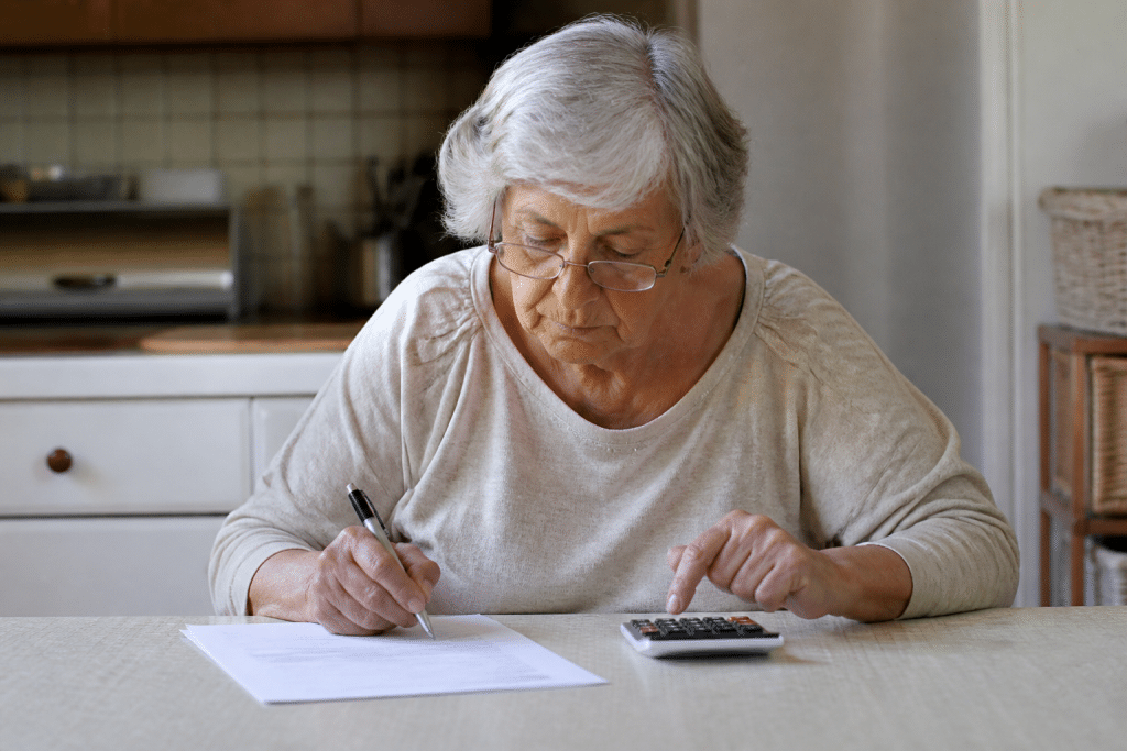 Personne agee signant document immobilier avec calculatrice