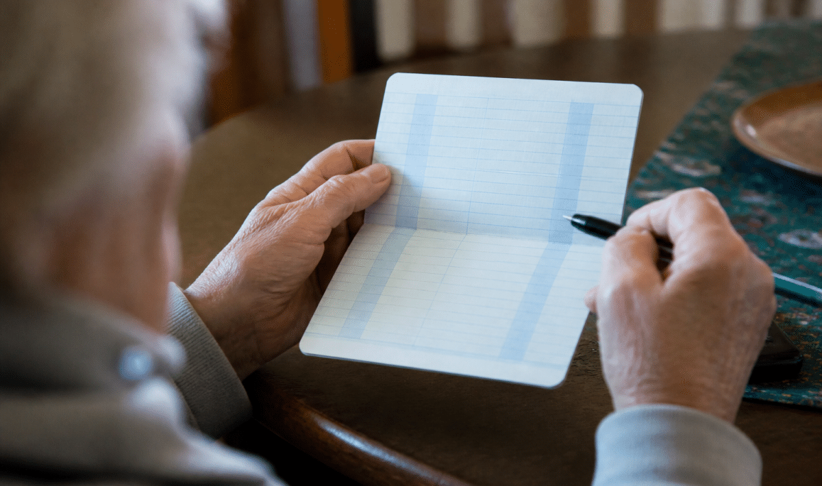Livret bancaire ouvert montrant solde diminué avec stylo pointant vers bas