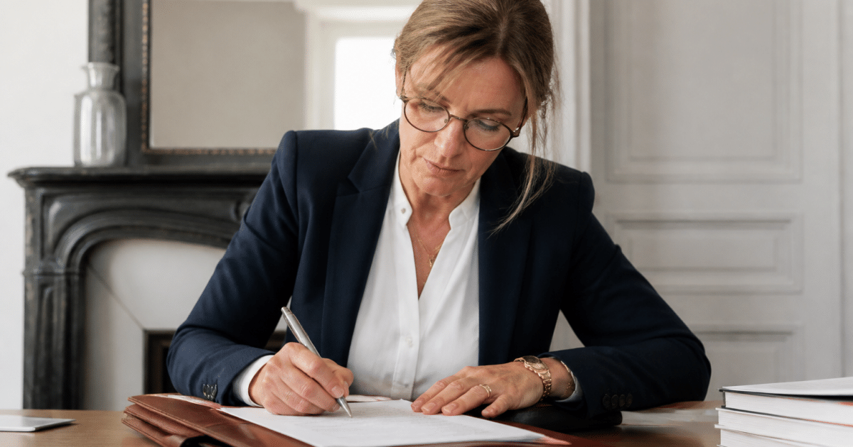 Notaire signant document immobilier avec stylo sur bureau