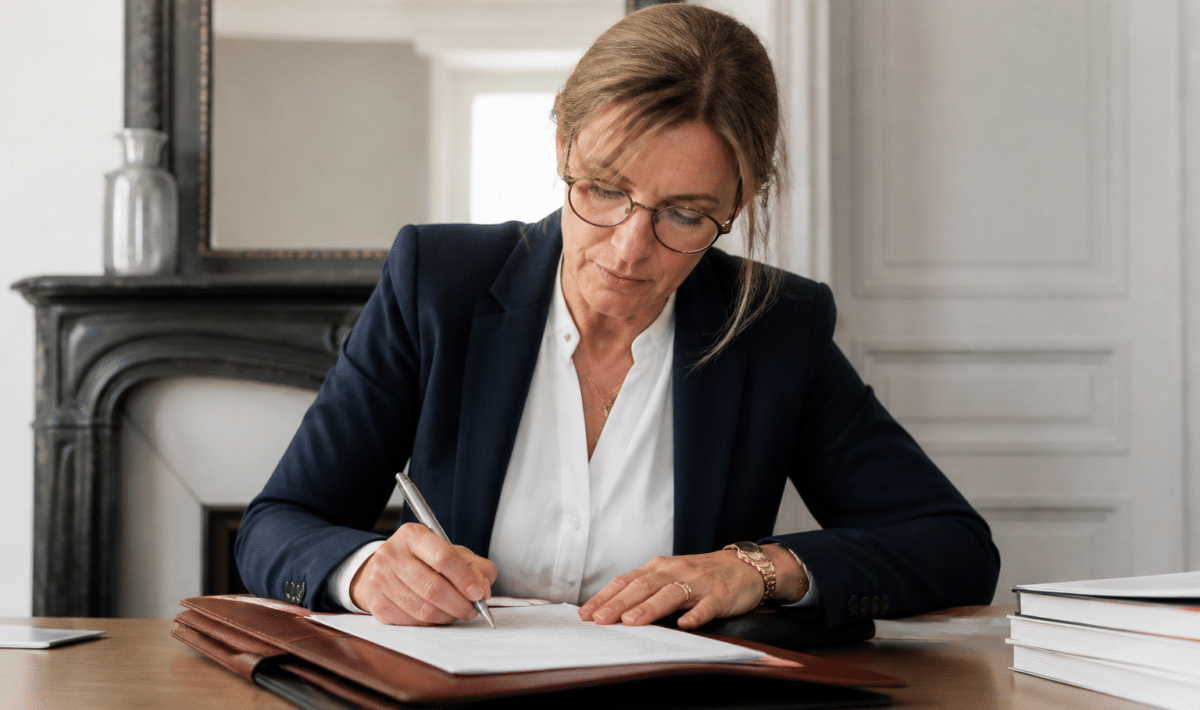 Notaire signant document immobilier avec stylo sur bureau