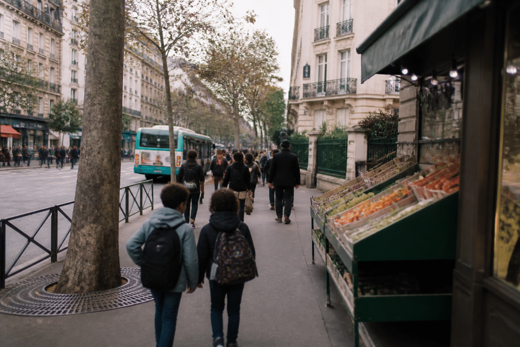 Rue animée avec commerces, école et panneau de transport visible