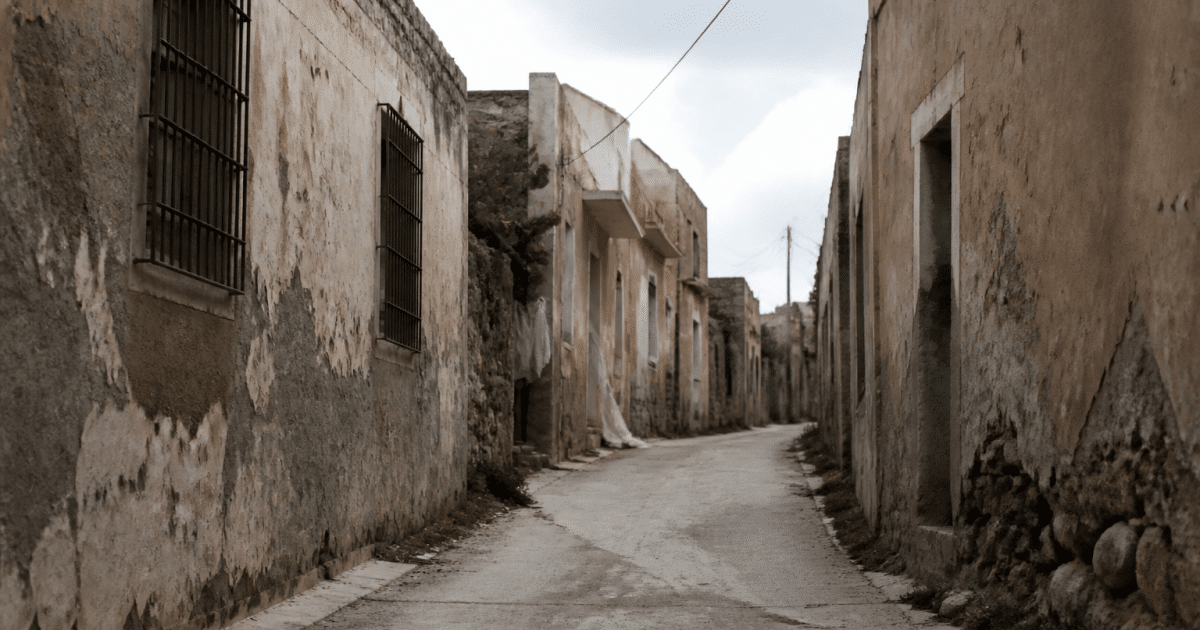 Rue deserteuse avec batiments decrépits et murs dégradés.