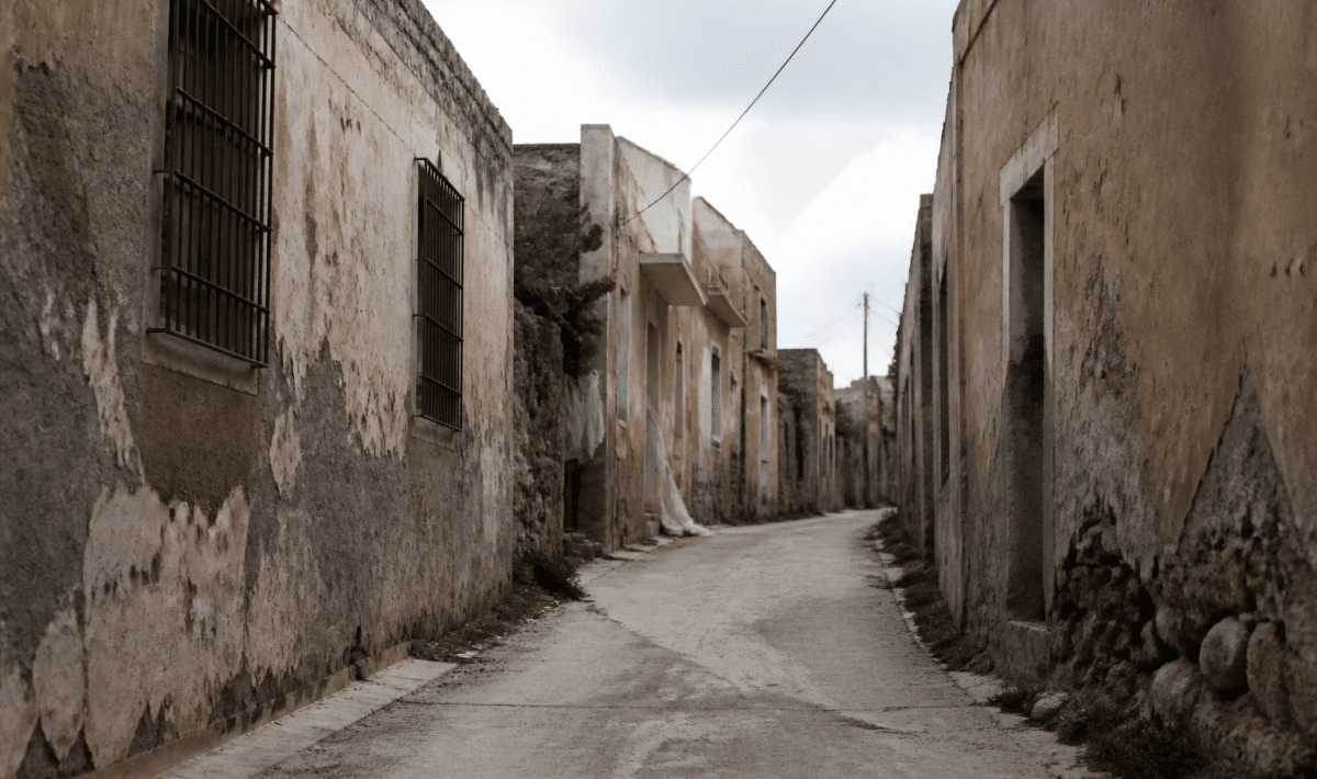 Rue deserteuse avec batiments decrépits et murs dégradés.