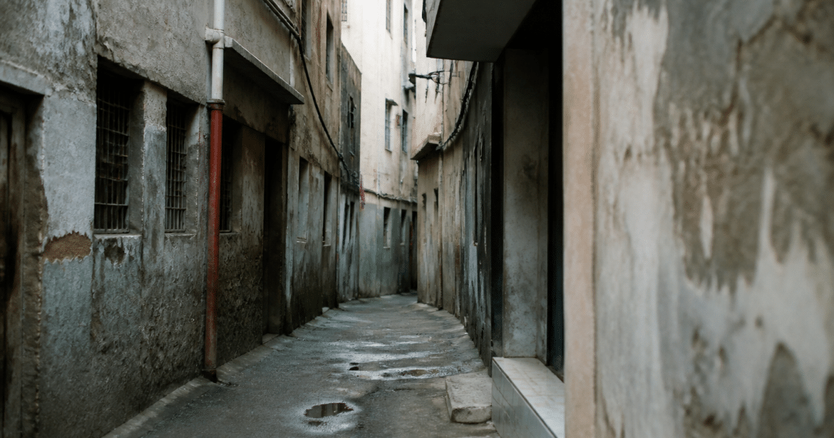 Rue étroite avec immeubles dégradés et murs gris délabérés
