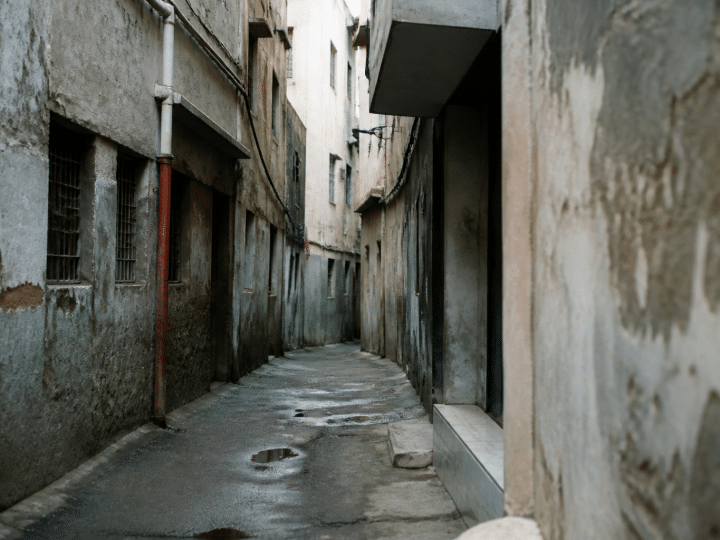 Rue étroite avec immeubles dégradés et murs gris délabérés