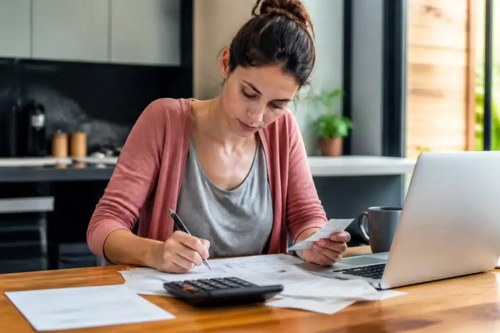 Femme signant documents fiscaux avec calculatrice et reçus