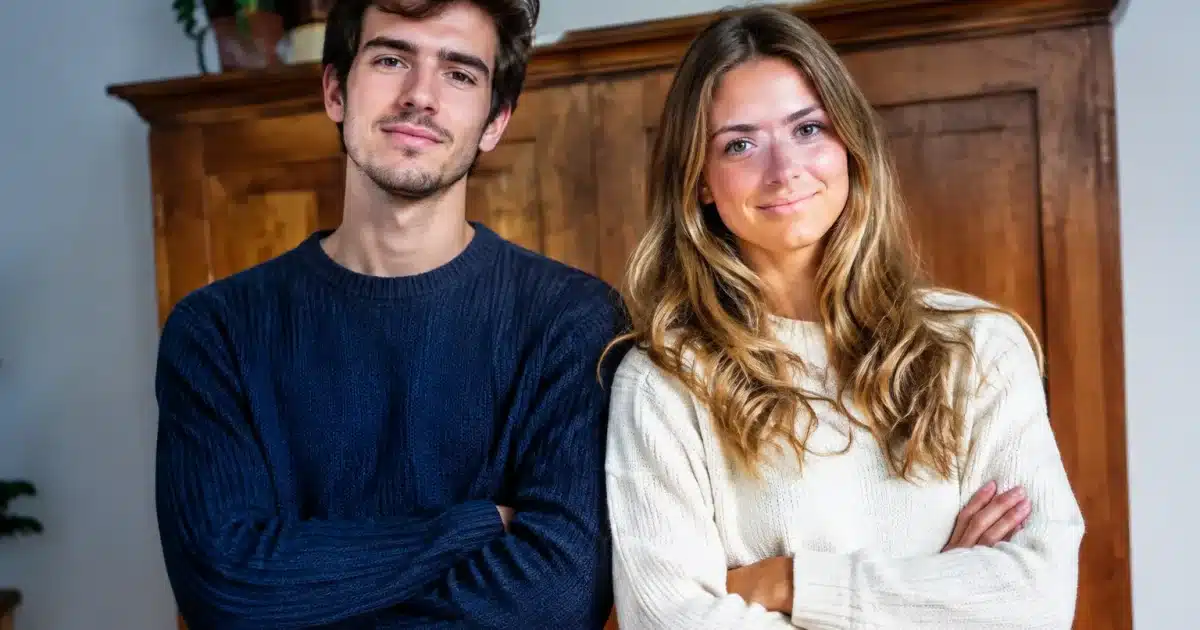 Deux jeunes adultes se tiennent devant un meuble en bois, les bras croisés