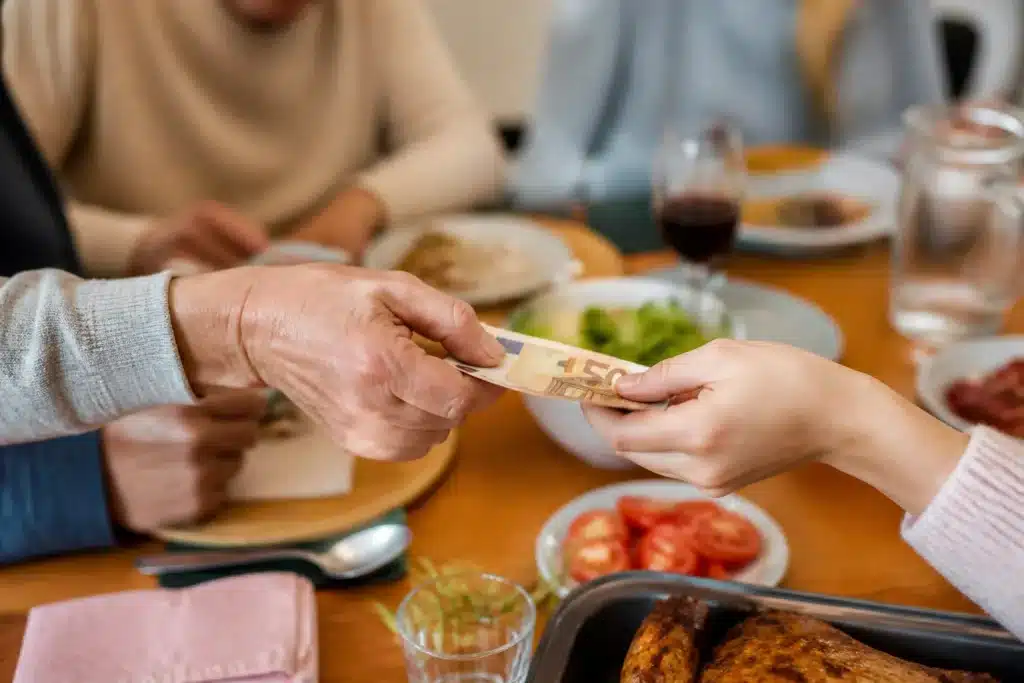 Mains echangeant billet argent autour table famille