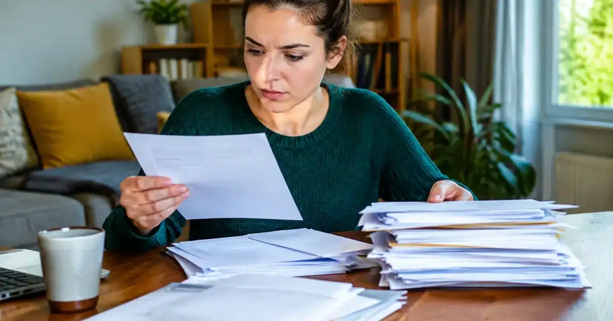 Personne assise tenant des factures et documents empiles devant elle