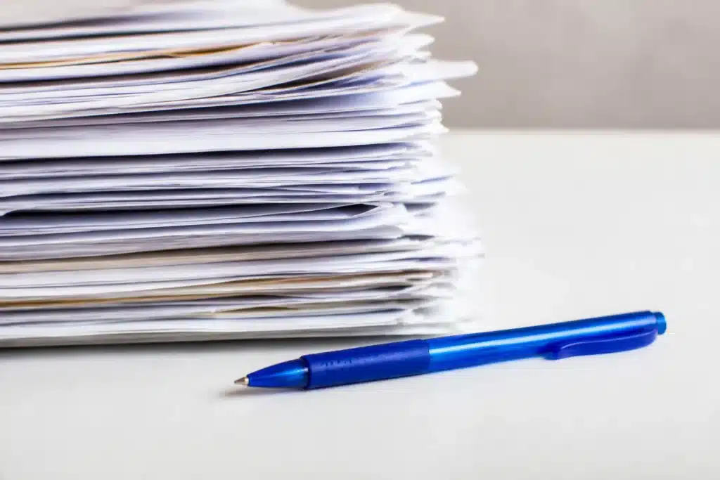 Pile de factures avec stylo bleu sur table blanche