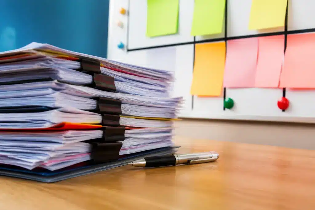 Pile de documents administratifs avec stylo et tableau organisé