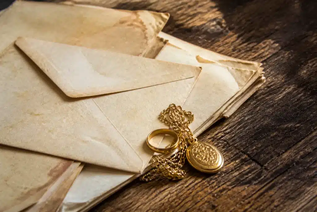 Enveloppe ancienne, lettres jaunie et bijoux or sur table bois