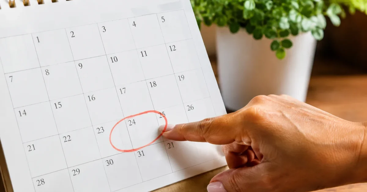 Main pointant les dates octobre sur un calendrier