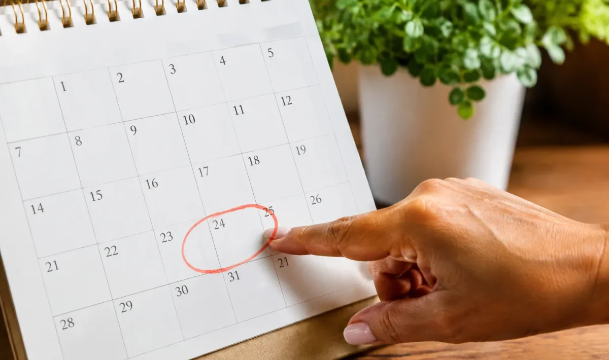 Main pointant les dates octobre sur un calendrier