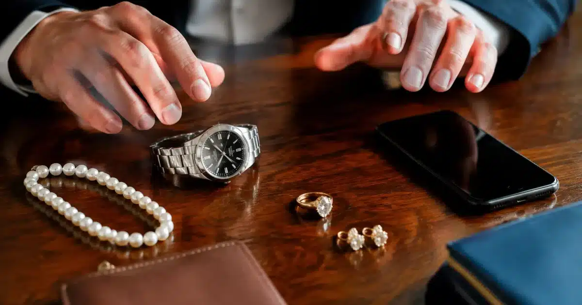 Objets de valeur disposés sur table, mains indecises au-dessus