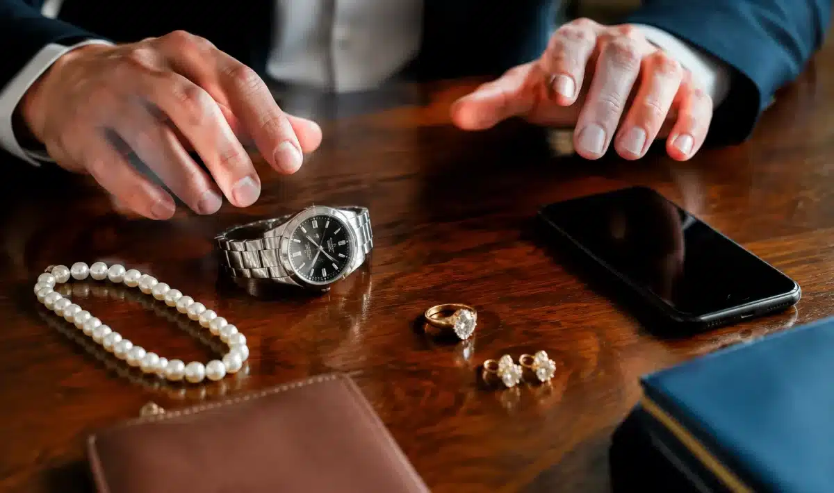 Objets de valeur disposés sur table, mains indecises au-dessus