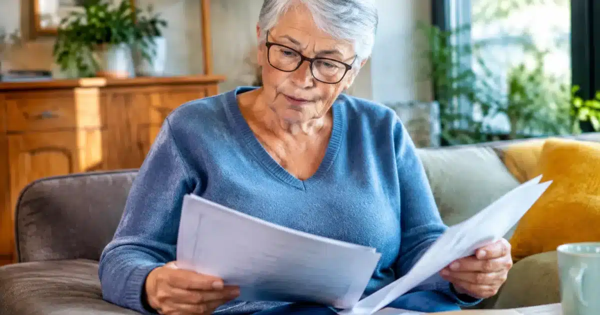 Personne agee assise tenant documents pension non reclames