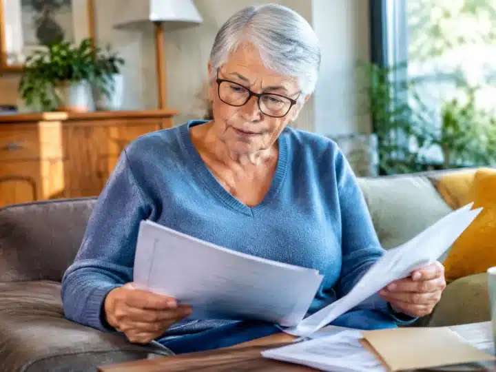 Personne agee assise tenant documents pension non reclames