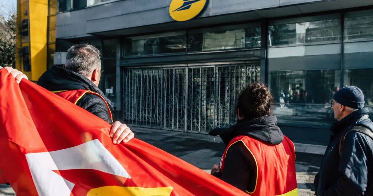 Pancarte syndicale déployée devant immeuble postal fermé