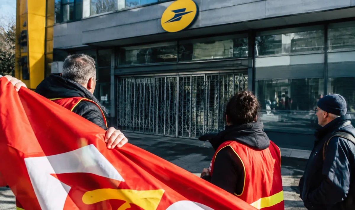 Pancarte syndicale déployée devant immeuble postal fermé