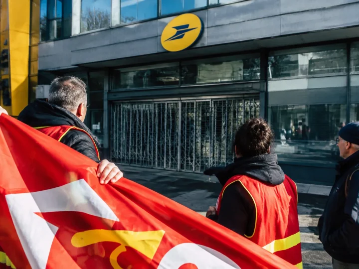 Pancarte syndicale déployée devant immeuble postal fermé