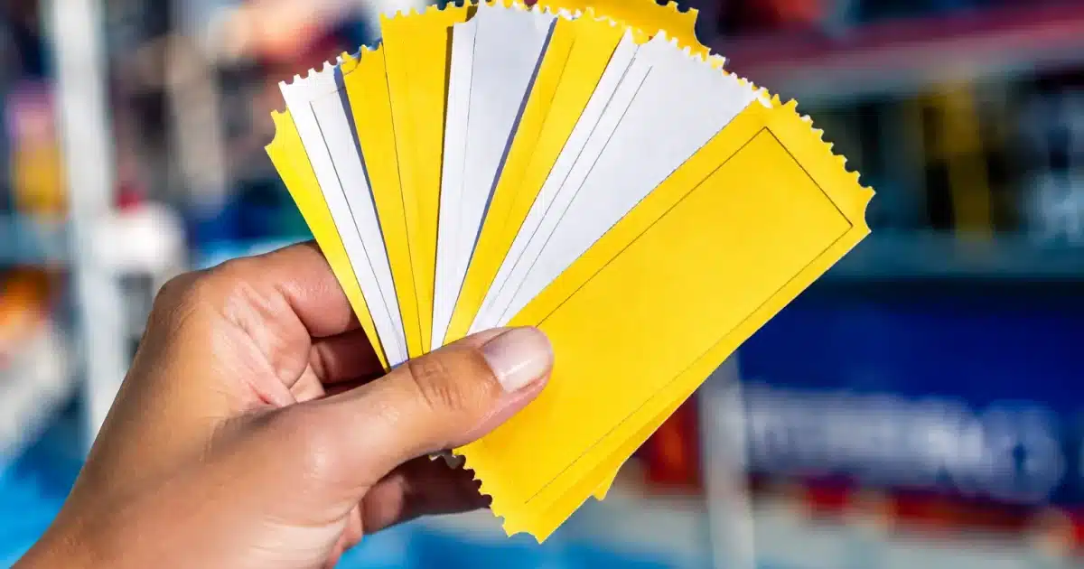Mains tenant pile de tickets carton jaunes et blancs