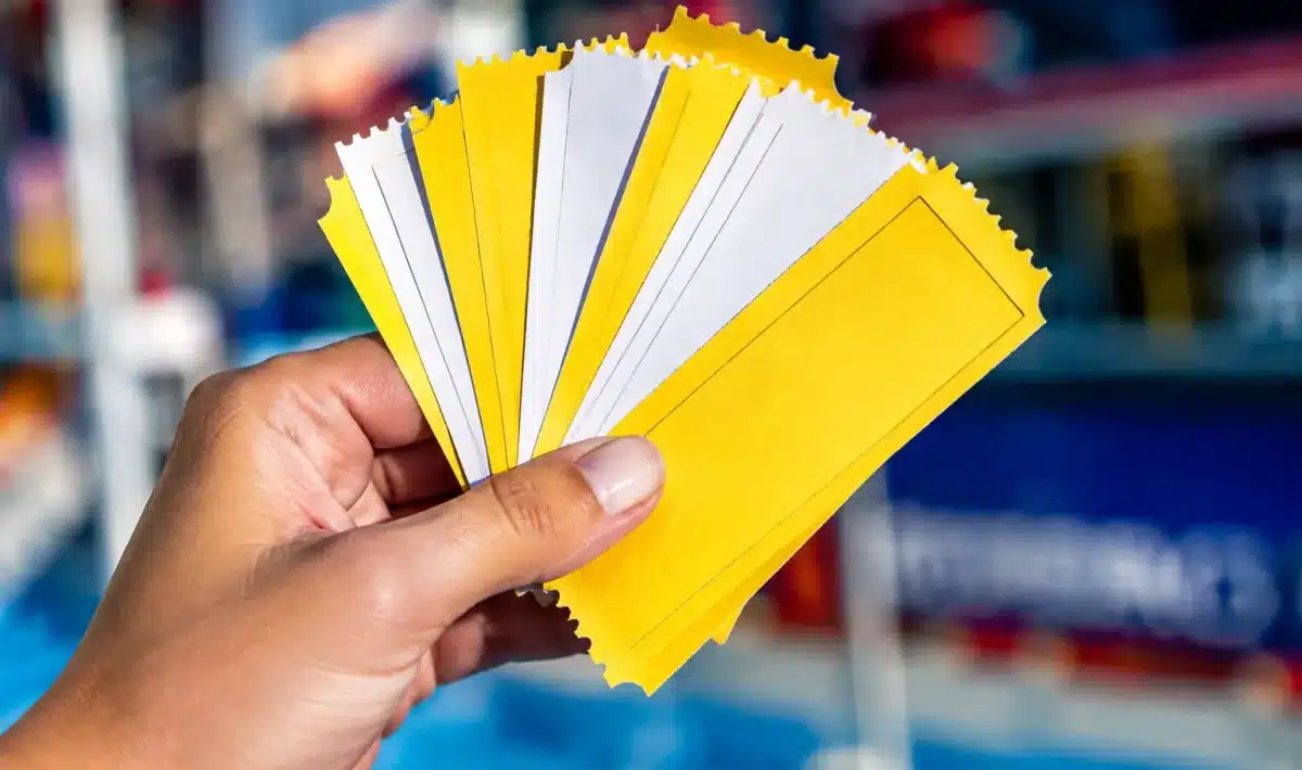 Mains tenant pile de tickets carton jaunes et blancs
