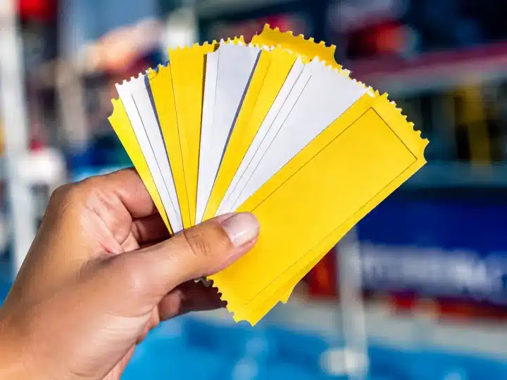 Mains tenant pile de tickets carton jaunes et blancs