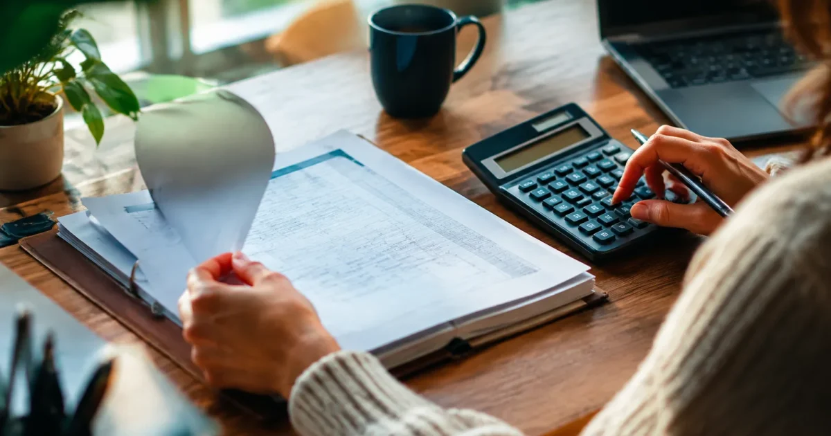 Dossier papier ouvert sur un bureau avec calculatrice