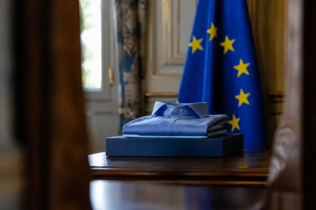 Une elue tient une chemise devant un drapeau europeen