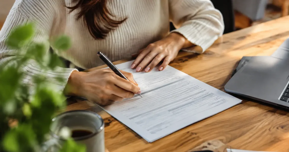 Femme assise signant un formulaire sur un bureau