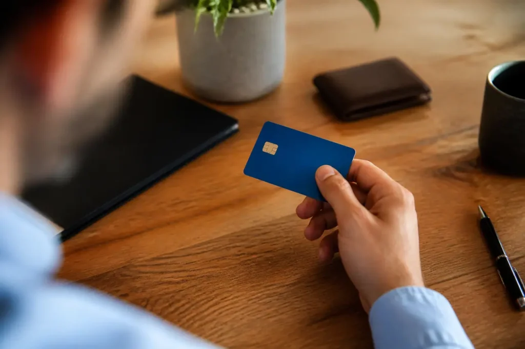 Une main tient une carte bleue sur un bureau