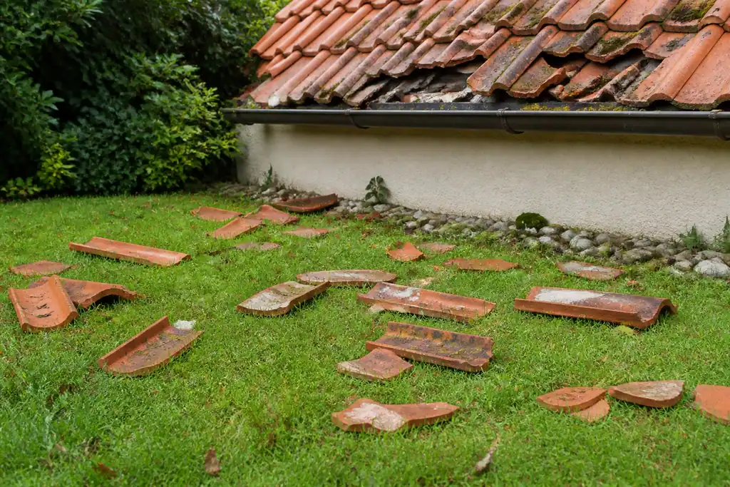 Toiture abimee avec tuiles eparpillees sur la pelouse